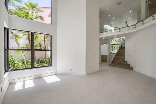 13890 Parc Dr, Palm Beach Gardens, FL 33410 - unfurnished living room featuring a towering ceiling, plenty of natural light, baseboards, stairs, and recessed lighting
