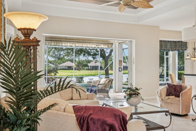 living area with light tile patterned floors, ceiling fan, a wealth of natural light, and a tray ceiling