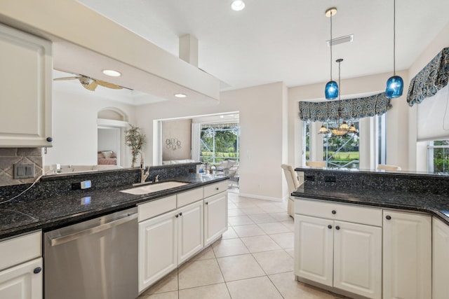 kitchen with white cabinetry, stainless steel dishwasher, a sink, light tile patterned flooring, and decorative light fixtures