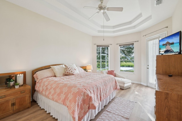 bedroom with ceiling fan, a raised ceiling, visible vents, light wood-type flooring, and access to outside