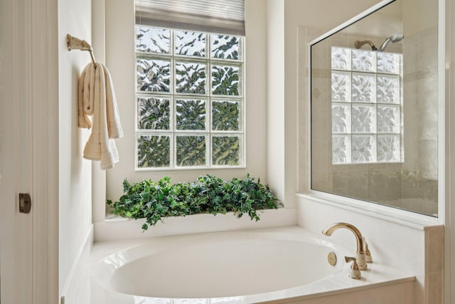 bathroom with a garden tub and a tile shower
