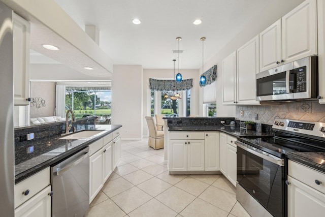 kitchen featuring a sink, stainless steel appliances, decorative backsplash, a peninsula, and white cabinets