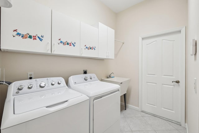 laundry room with light tile patterned floors, washer and dryer, cabinet space, and baseboards