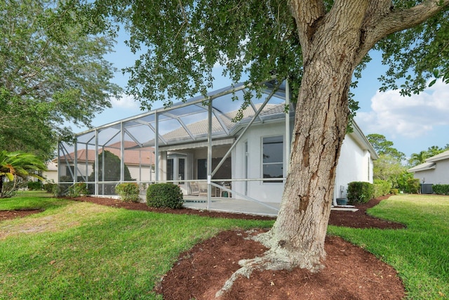 back of property featuring stucco siding, a patio area, a lanai, cooling unit, and a lawn