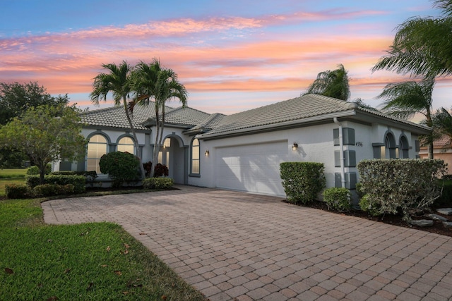 view of front of house featuring a tile roof, a garage, stucco siding, and decorative driveway