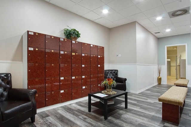 living area featuring wood finished floors, a paneled ceiling, visible vents, and wainscoting