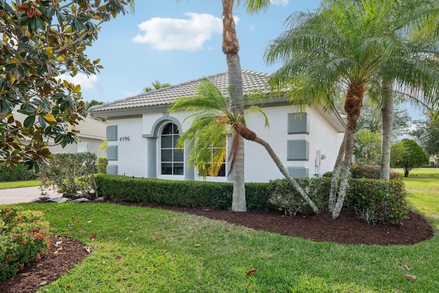 view of side of home with a yard, stucco siding, and a tiled roof