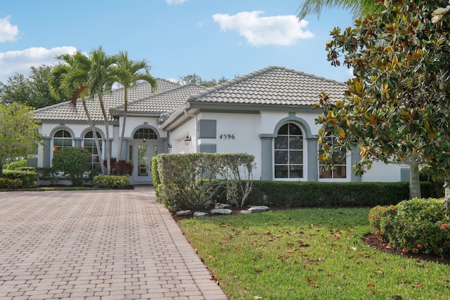mediterranean / spanish-style home featuring stucco siding, a front yard, and a tiled roof