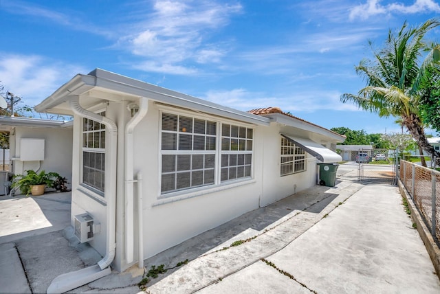 391 SW 2nd St, Boca Raton, FL 33432 - view of property exterior featuring fence, a patio, stucco siding, a tile roof, and a gate