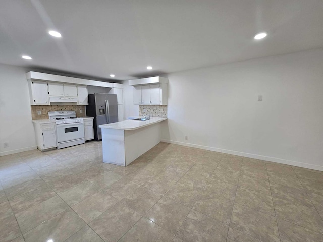 6363 Seven Springs Blvd Unit B, Greenacres, FL 33463 - kitchen with decorative backsplash, under cabinet range hood, white range with gas stovetop, and stainless steel fridge