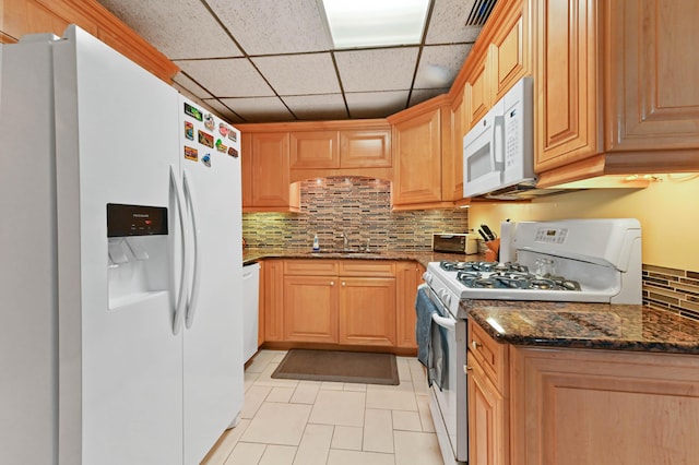 5725 Basil Dr, West Palm Beach, FL 33415 - kitchen with white appliances, light tile patterned floors, decorative backsplash, a sink, and dark stone countertops