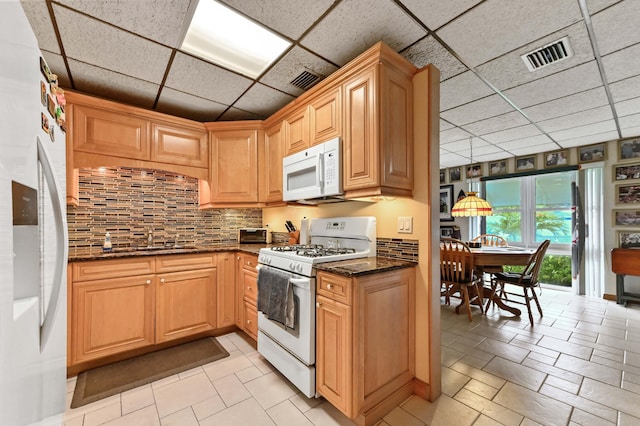 5725 Basil Dr, West Palm Beach, FL 33415 - kitchen with white appliances, a drop ceiling, dark stone counters, a sink, and backsplash