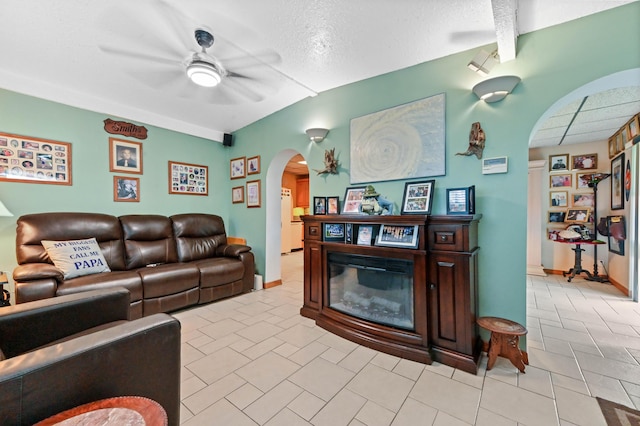 5725 Basil Dr, West Palm Beach, FL 33415 - living area featuring arched walkways, a ceiling fan, a glass covered fireplace, a textured ceiling, and light tile patterned flooring