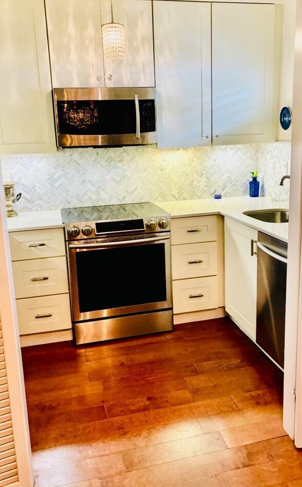 139 Sunrise Ave Unit 1050, Palm Beach, FL 33480 - kitchen featuring a sink, white cabinetry, dark wood-type flooring, light countertops, and appliances with stainless steel finishes
