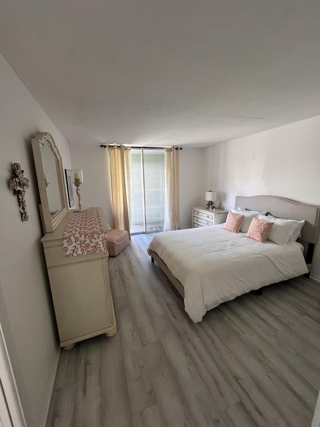bedroom featuring access to outside, light wood-style flooring, and baseboards