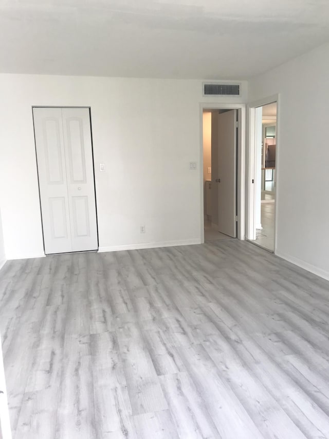 empty room with baseboards, wood finished floors, and visible vents