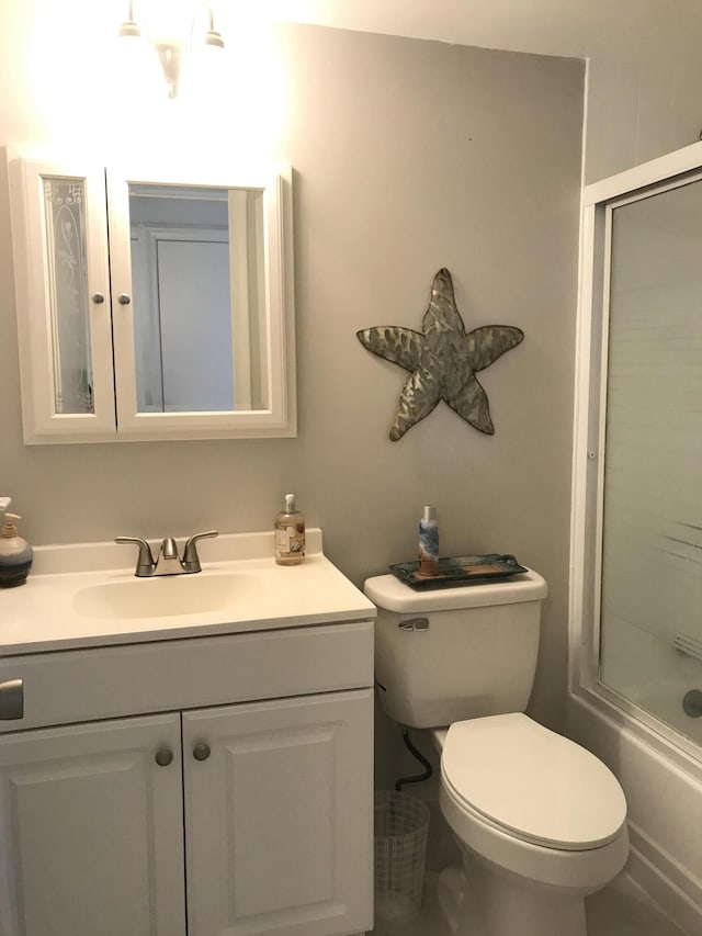 bathroom with vanity, combined bath / shower with glass door, and toilet