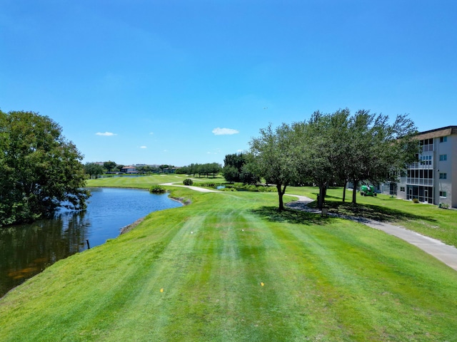 view of property's community with view of golf course, a yard, and a water view