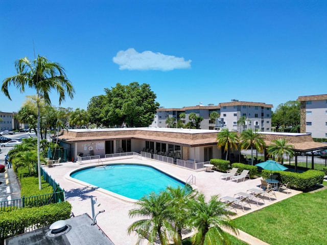 pool featuring fence, a patio area, and a lawn