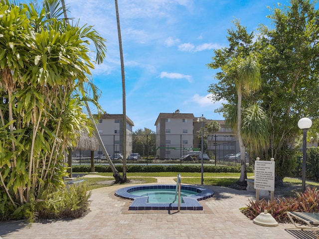 view of property's community with fence and a hot tub