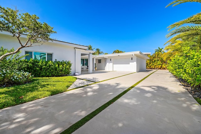 view of front of home with stucco siding, an attached garage, and concrete driveway