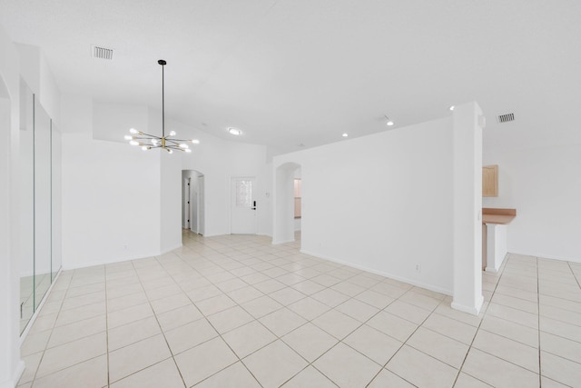 unfurnished room featuring arched walkways, an inviting chandelier, vaulted ceiling, and visible vents