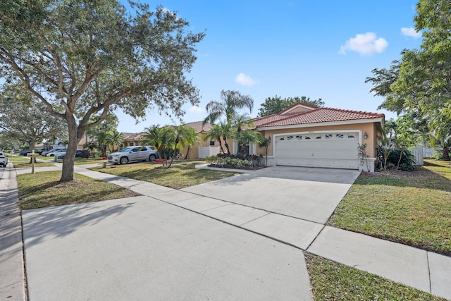 mediterranean / spanish home featuring a tiled roof, stucco siding, a front lawn, an attached garage, and concrete driveway