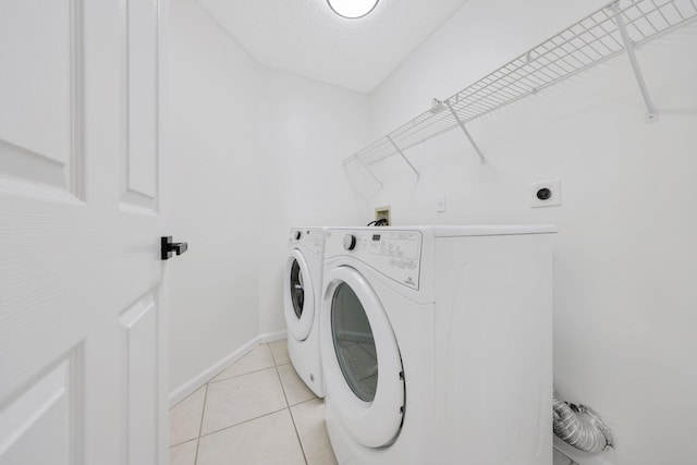 laundry room featuring independent washer and dryer, light tile patterned floors, laundry area, and baseboards
