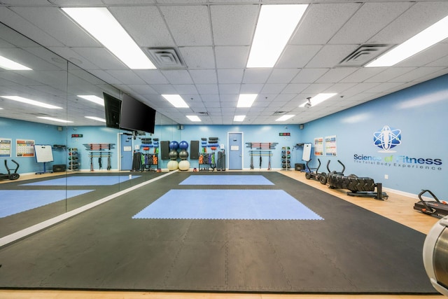 exercise room featuring visible vents, baseboards, and a paneled ceiling