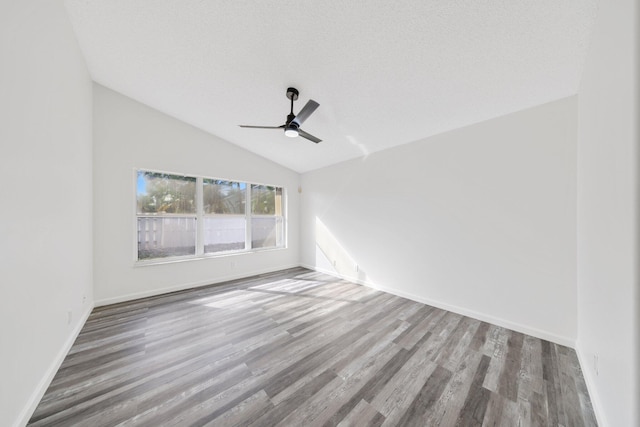 unfurnished room with wood finished floors, baseboards, a ceiling fan, and vaulted ceiling