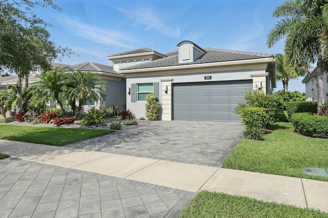 view of front of house with an attached garage, a front yard, decorative driveway, and stucco siding
