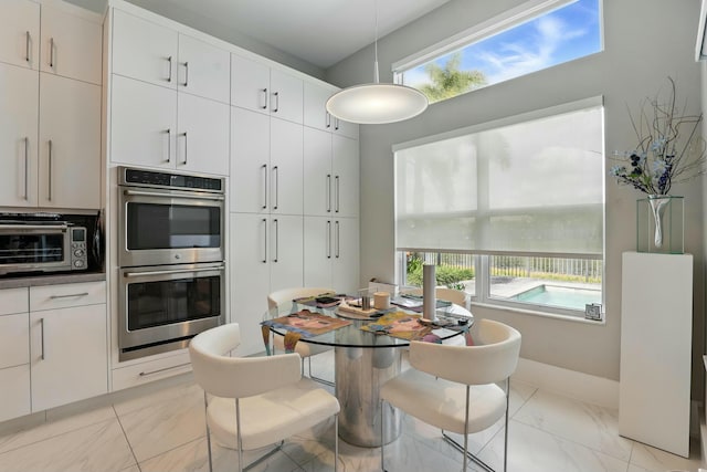 dining area featuring plenty of natural light, marble finish floor, and a toaster