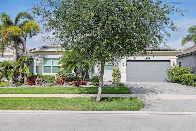 obstructed view of property with a garage, stucco siding, driveway, and a front yard