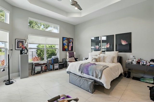 bedroom with marble finish floor, a ceiling fan, a towering ceiling, and a raised ceiling