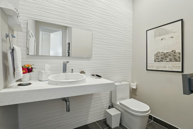 half bath with tasteful backsplash, a sink, baseboards, toilet, and tile patterned flooring