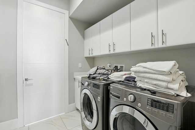 washroom featuring marble finish floor, washing machine and clothes dryer, and cabinet space