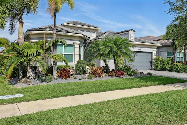 mediterranean / spanish house featuring driveway, a front lawn, stucco siding, and an attached garage