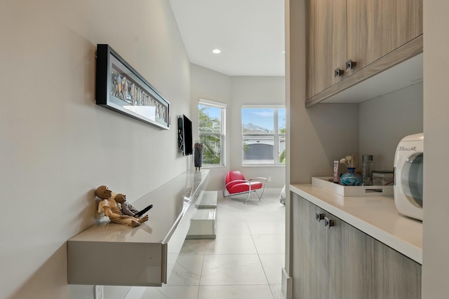 interior space featuring light tile patterned flooring, baseboards, recessed lighting, and cabinet space
