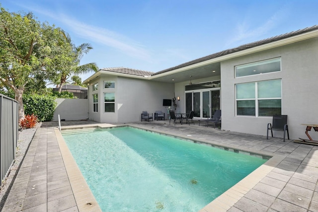 back of house featuring fence private yard, a patio area, a ceiling fan, an outdoor pool, and stucco siding