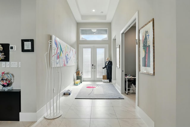 entrance foyer featuring baseboards, a healthy amount of sunlight, french doors, and a towering ceiling