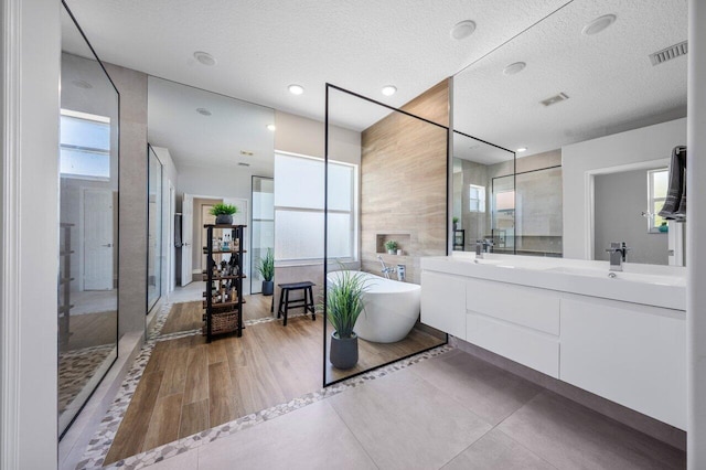 2261 Balsan Way, Wellington, FL 33414 - full bathroom with a freestanding bath, plenty of natural light, walk in shower, double vanity, and a textured ceiling