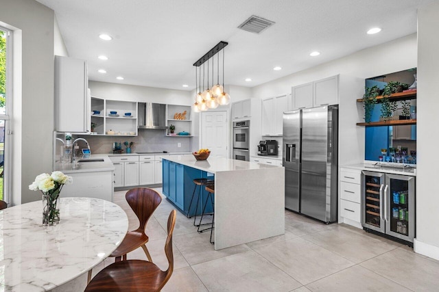 2261 Balsan Way, Wellington, FL 33414 - kitchen featuring appliances with stainless steel finishes, open shelves, beverage cooler, a sink, and a center island