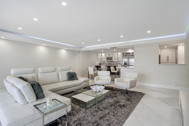 living room featuring a tray ceiling, baseboards, and recessed lighting