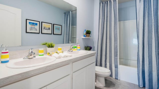 bathroom with double vanity, toilet, shower / bath combo, and a sink
