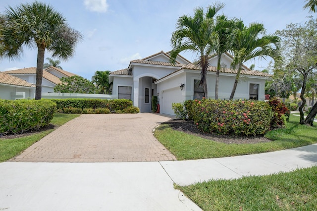 view of front of house featuring stucco siding, an attached garage, a tile roof, and decorative driveway