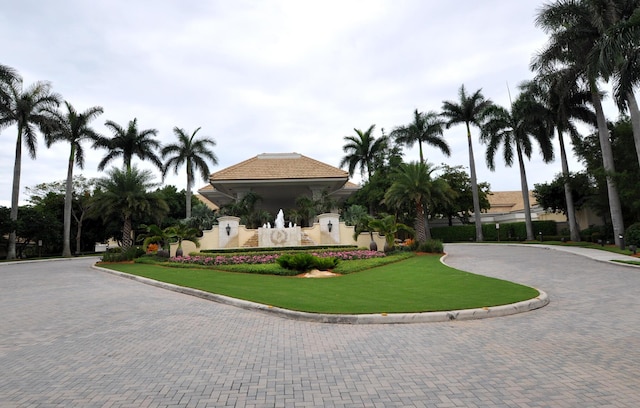 view of front of house featuring stucco siding, a tile roof, and a front yard