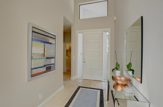 foyer entrance with a towering ceiling and baseboards