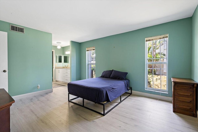 1521 NW 19th Ter Unit 101, Delray Beach, FL 33445 - bedroom featuring light wood-style floors, multiple windows, baseboards, and connected bathroom