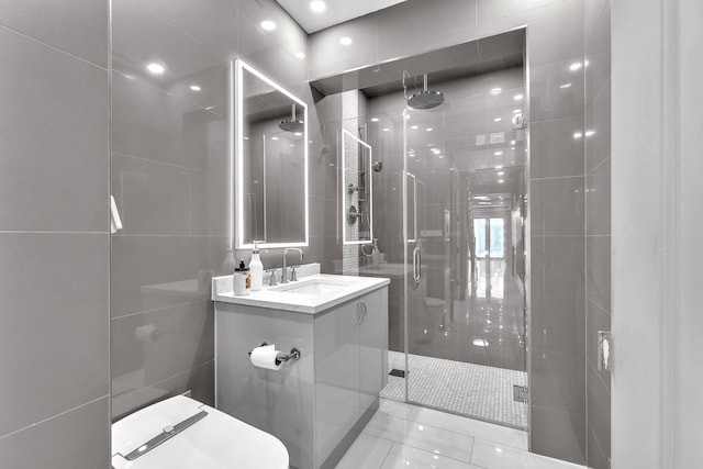 bathroom featuring tile walls, vanity, a shower stall, and toilet