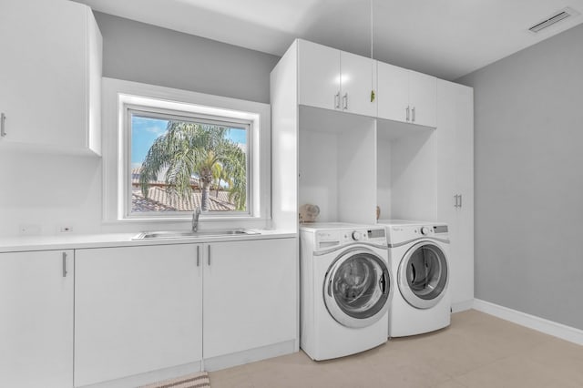 laundry room featuring visible vents, light tile patterned floors, a sink, separate washer and dryer, and cabinet space